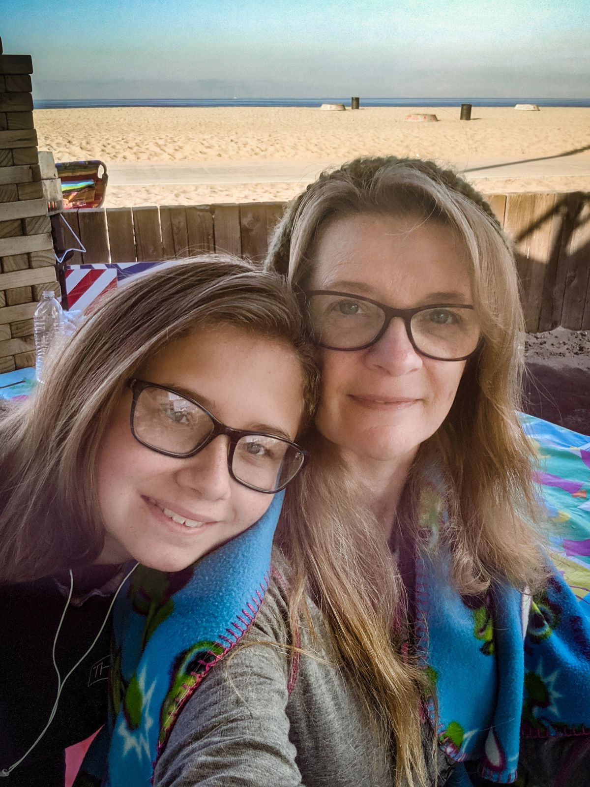 A mother and daughter sitting at a beach campsite taking a selfy with the beach in the background