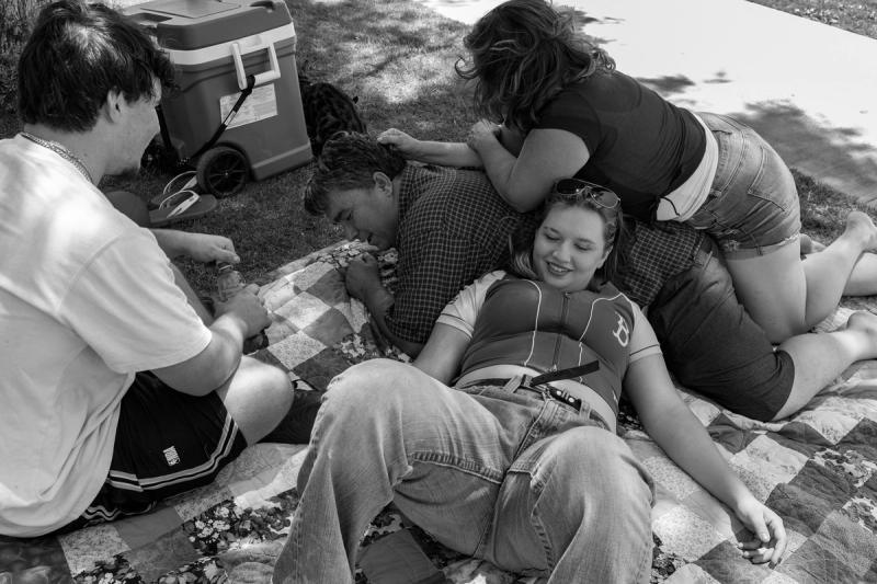 A family relaxing on a picnic blanket outdoors.