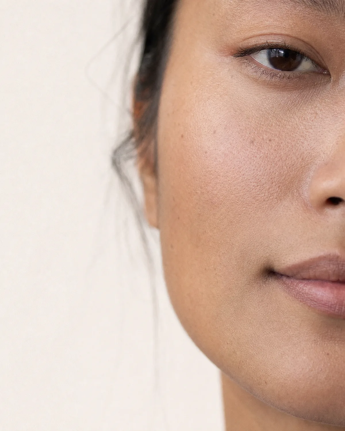 Close-up of a woman’s face in soft natural light, showing real, healthy skin texture