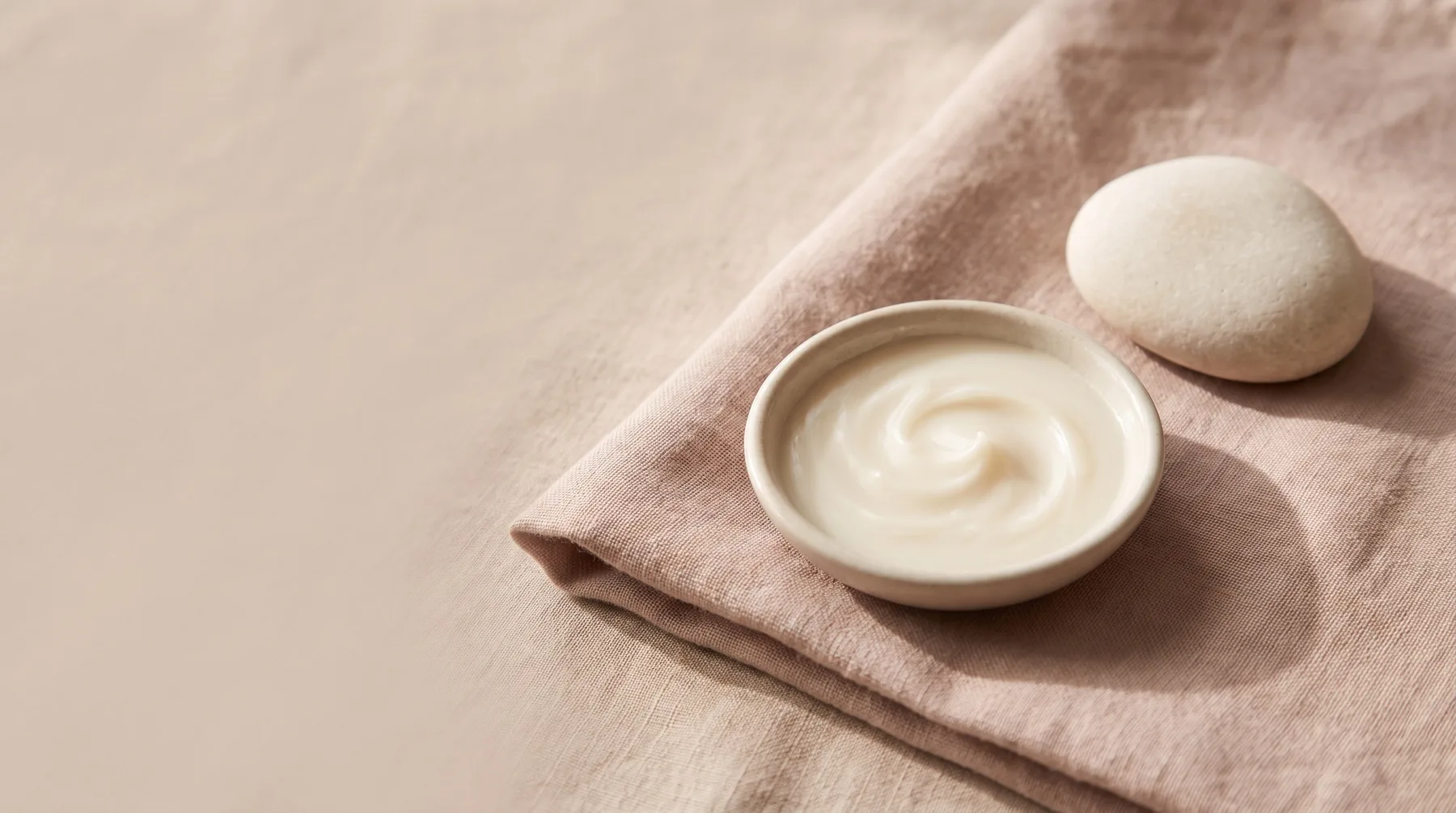 Ceramides — a dish of pale ivory ceramide balm beside a smooth pale stone on warm linen