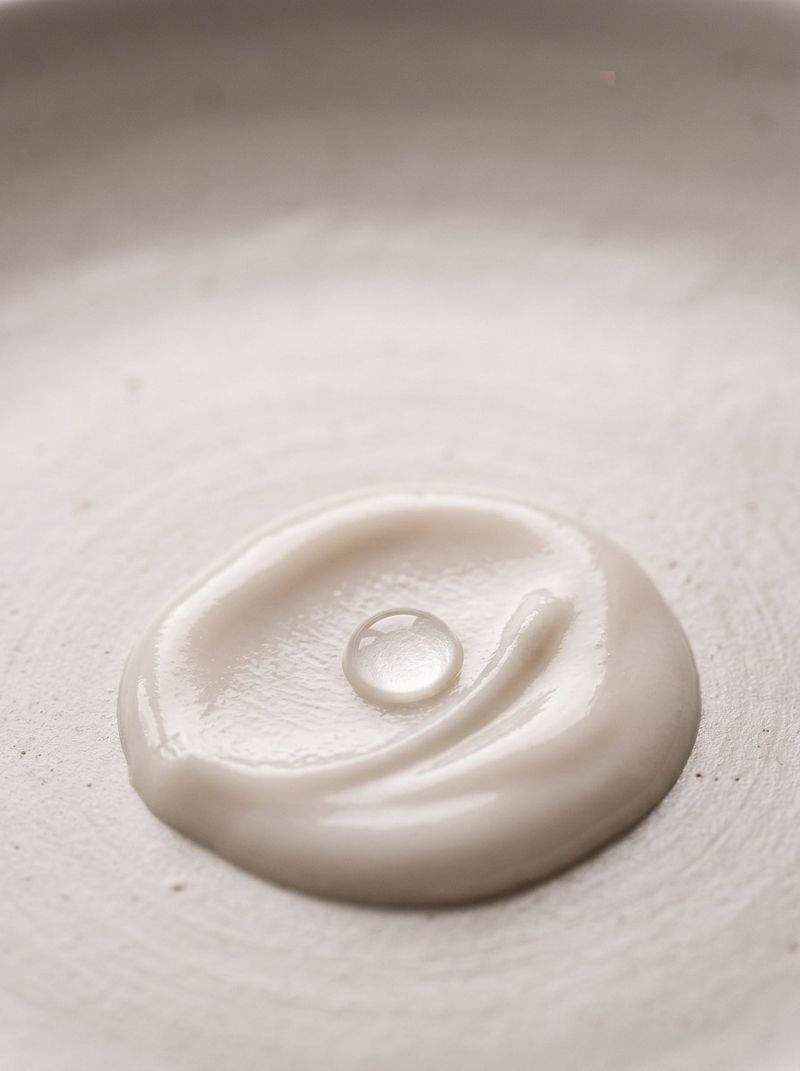 Macro close-up of a cream pool with a single dewdrop — actives for post-inflammatory hyperpigmentation