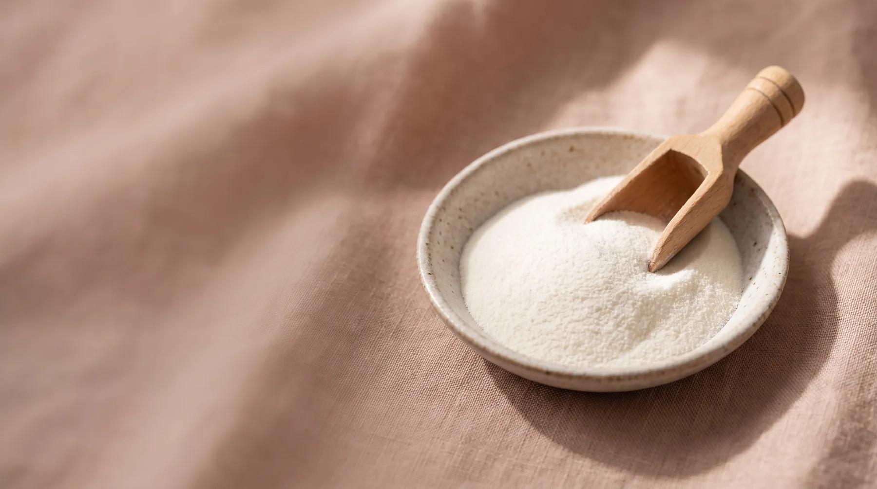 Peptides — a ceramic dish of fine white peptide powder with a wooden scoop on warm linen