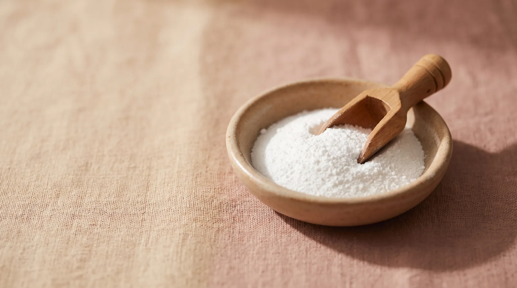 Vitamin B3 — a ceramic dish of fine white niacinamide powder with a wooden scoop on warm linen
