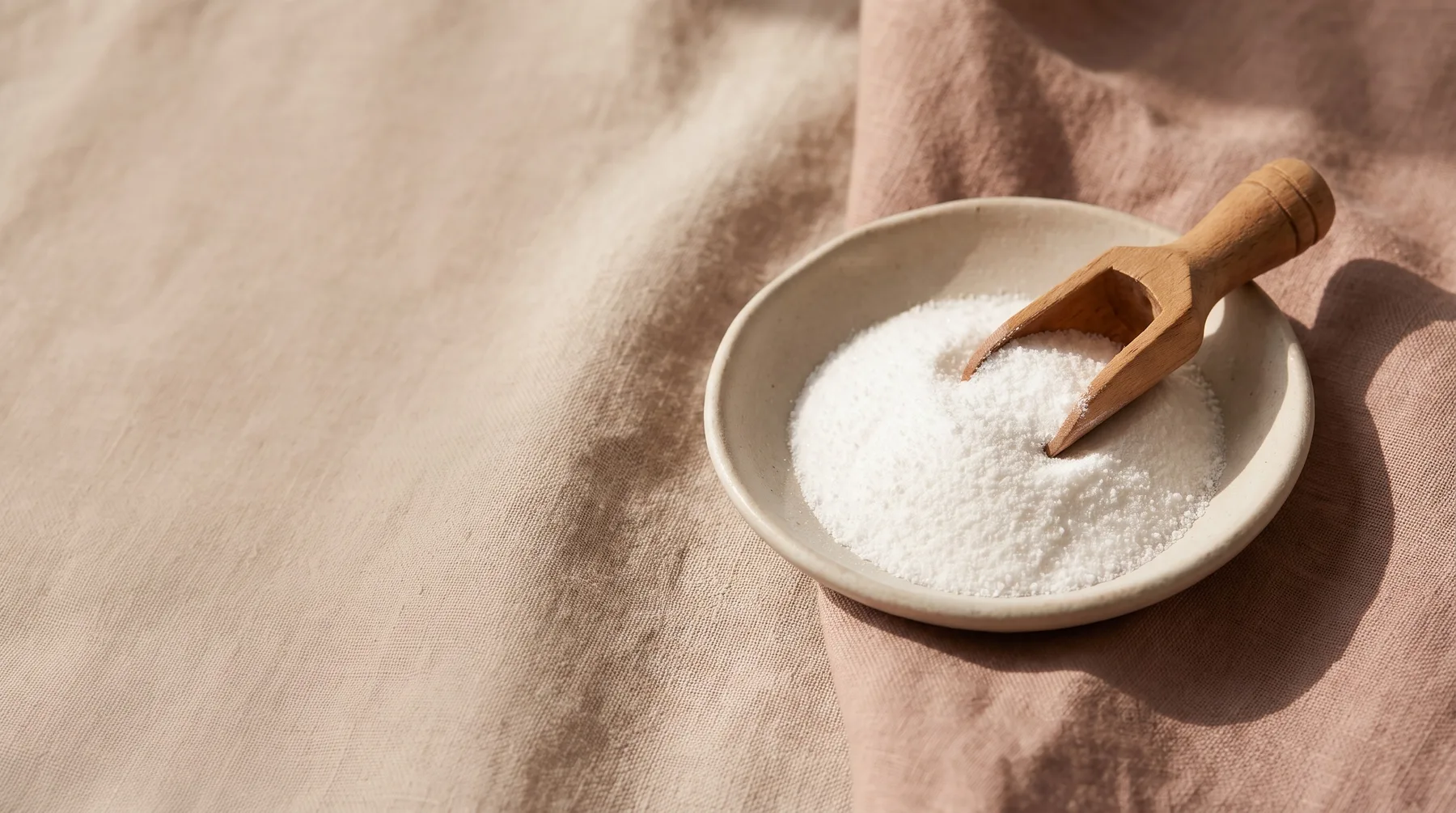 Arginine — a ceramic dish of fine white arginine powder with a wooden scoop on warm linen