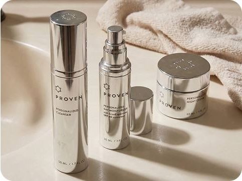 Three Proven skincare products—cleanser, moisturizer and night cream—displayed in silver packaging on a bathroom counter with a towel.