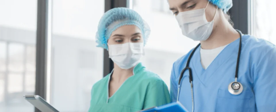 two healthcare workers reviewing a record while wearing masks to represent beacon free access being offered to hospitals in the wake of covid 19