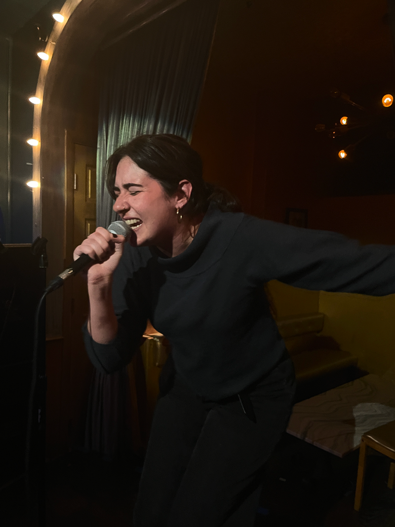 abigail singing into a karaoke mic in new york city - beardwood