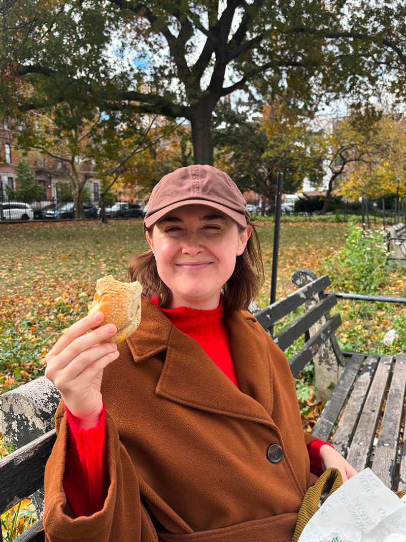 olivia eating a bagel in a new york city park - beardwood