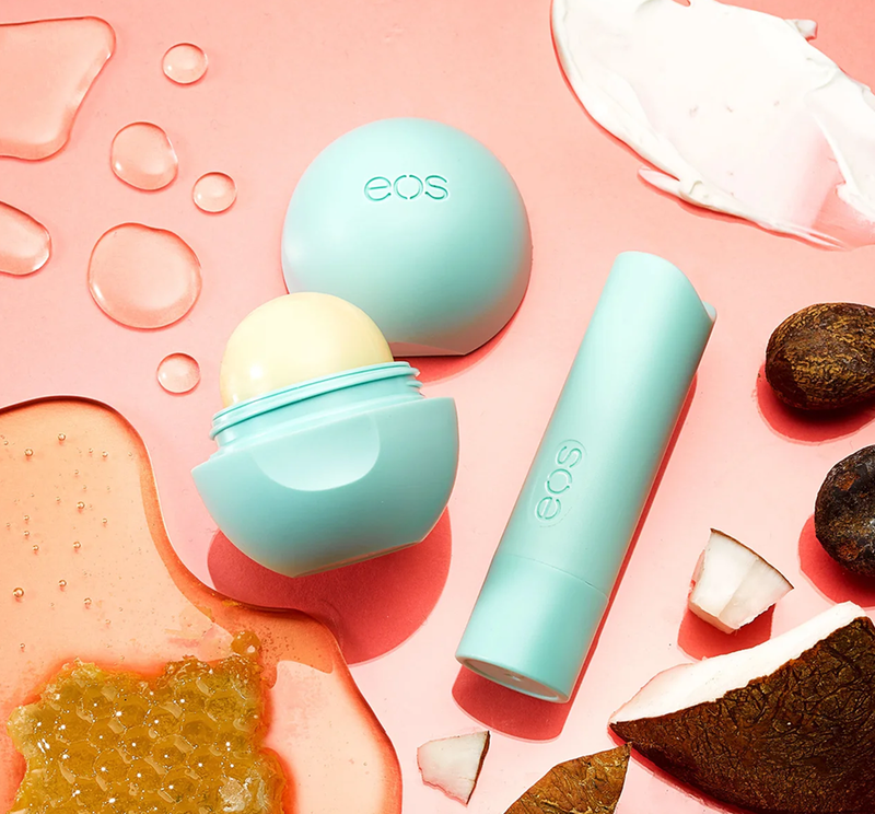 eos lip balm in the center with drops of liquid, honeycomb, lotion and coconut surrounding it  - beardwood