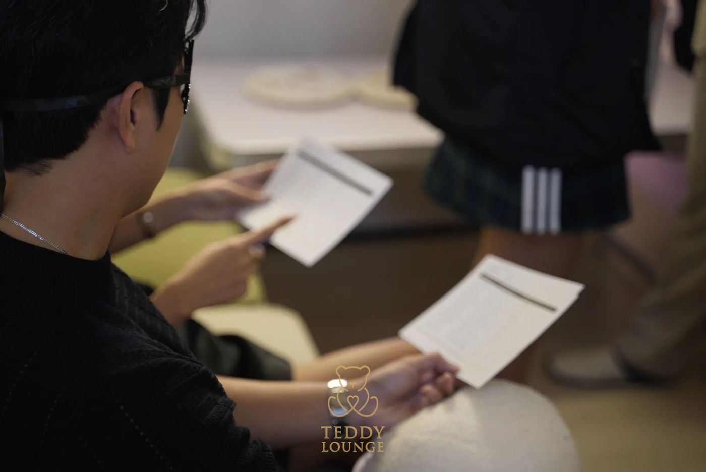 Masked Teddy Lounge guests read printed conversation cards.