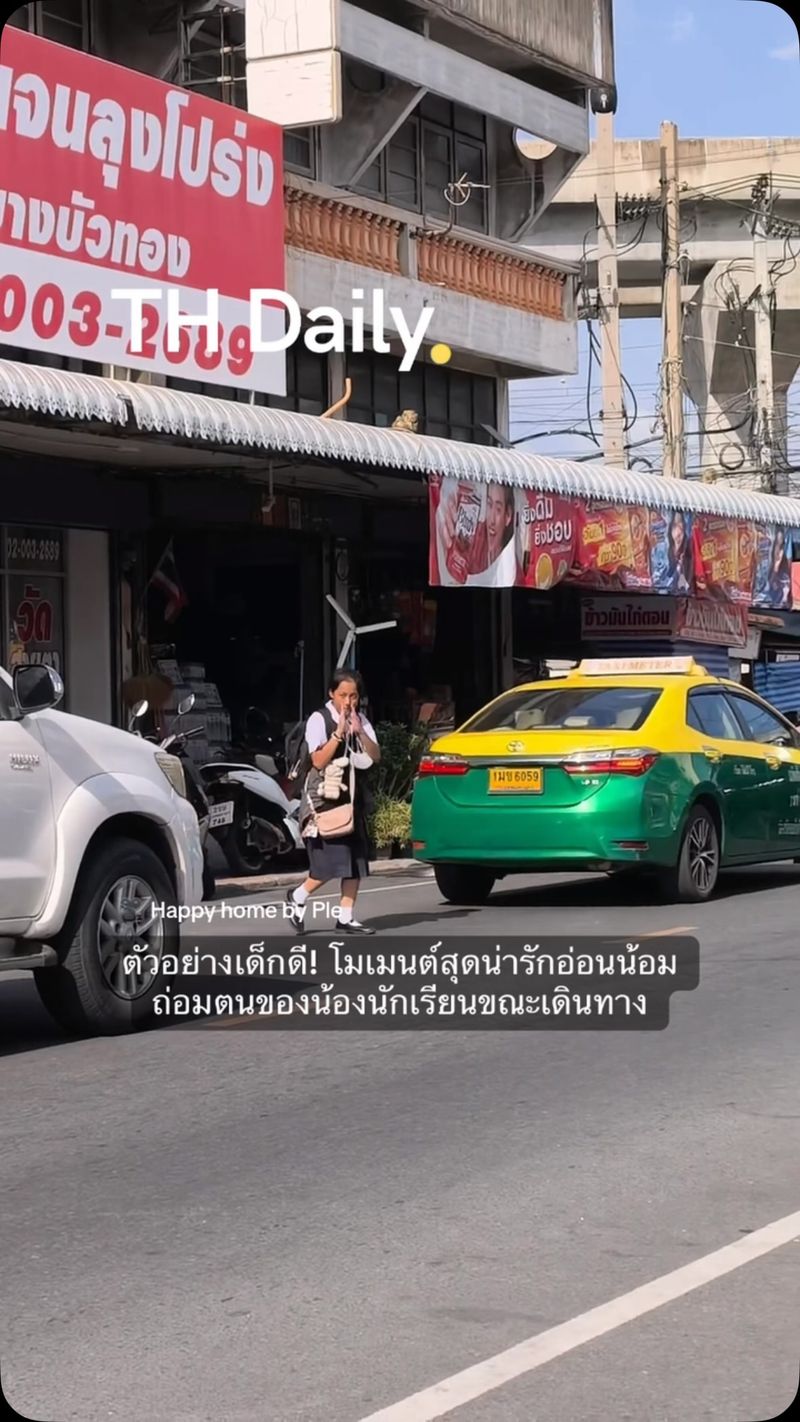 Young student gives wai while crossing busy road in Thailand
