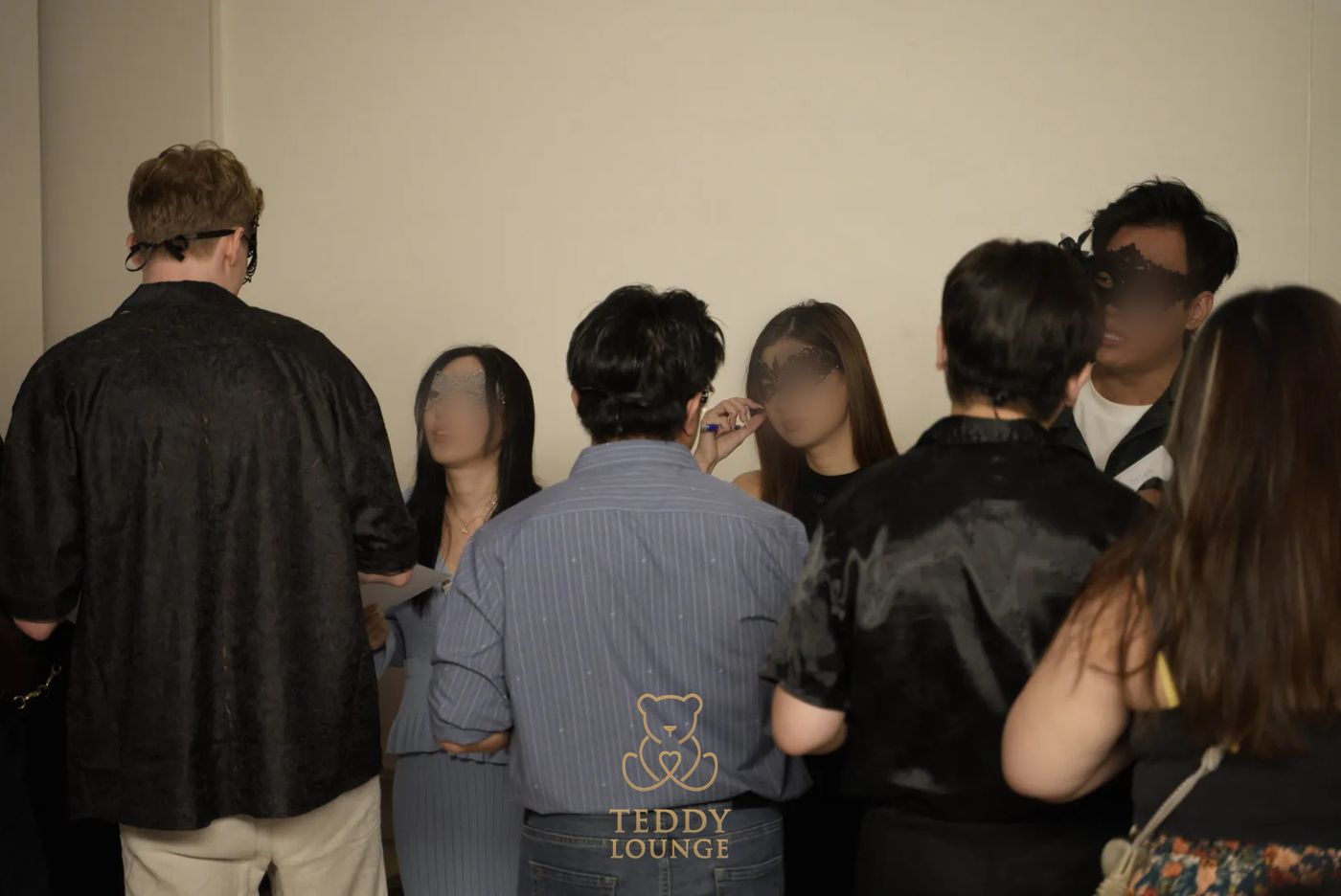 A group of masked guests mingle at the Teddy Lounge masquerade.