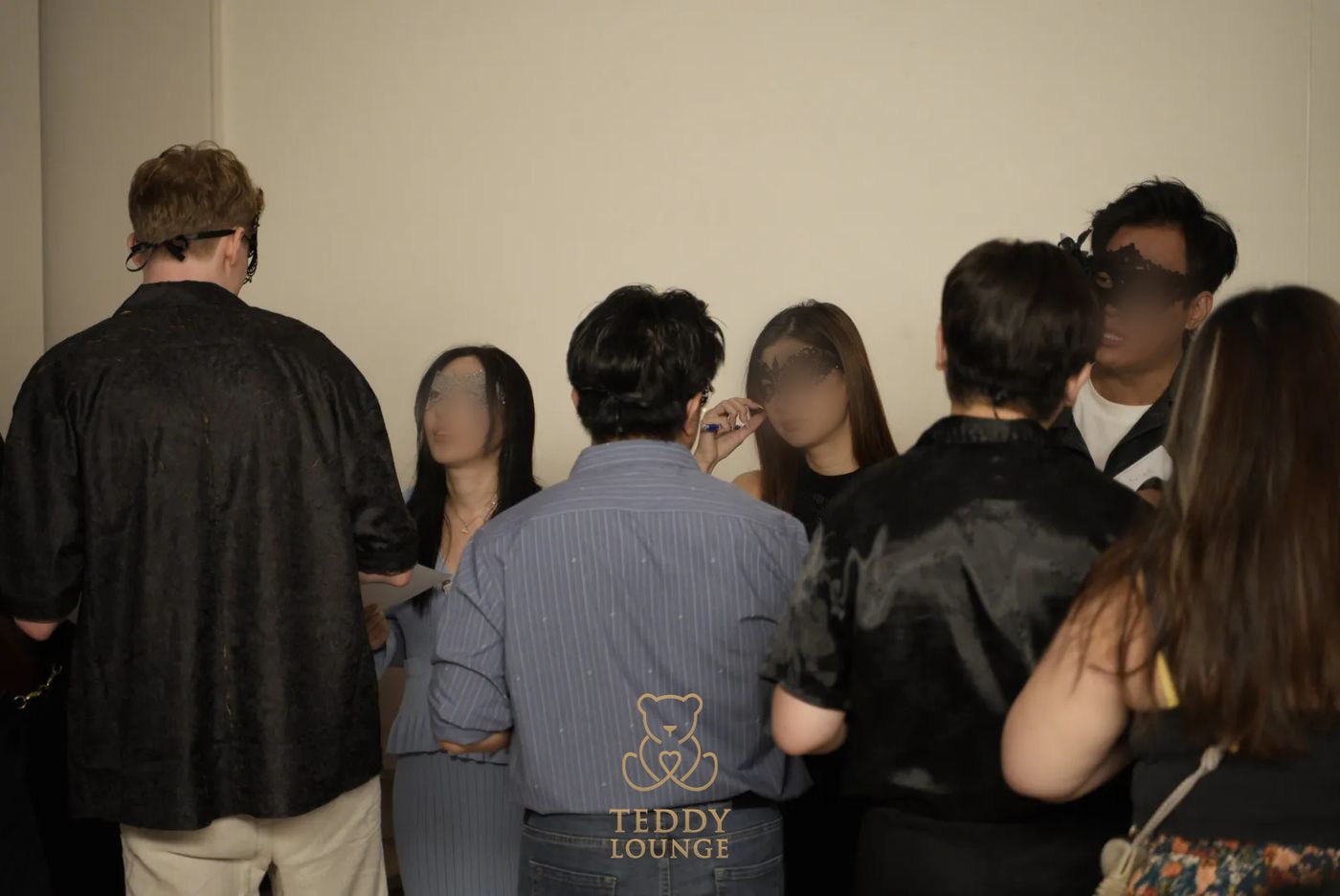 A group of masked guests mingle at the Teddy Lounge masquerade.