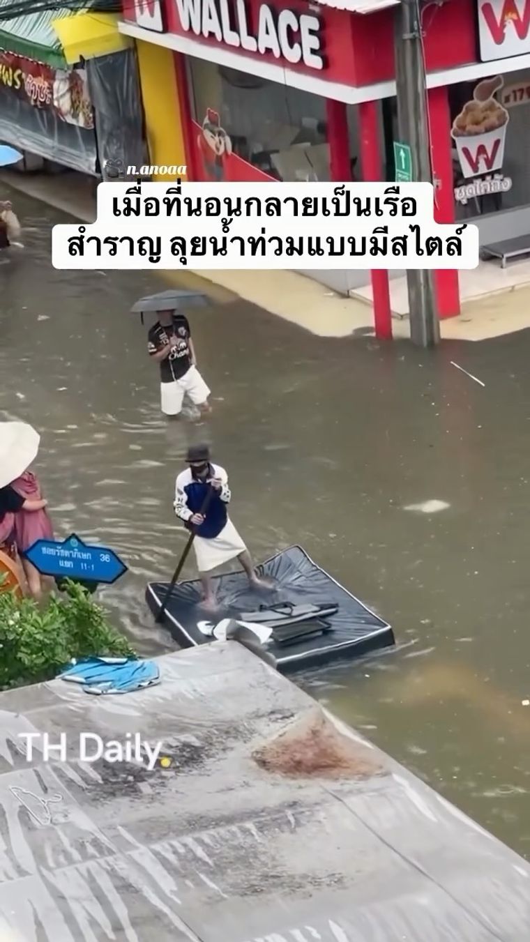 Person paddles a mattress through a flooded street
