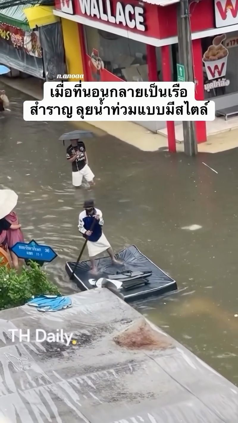 Person paddles a mattress through a flooded street