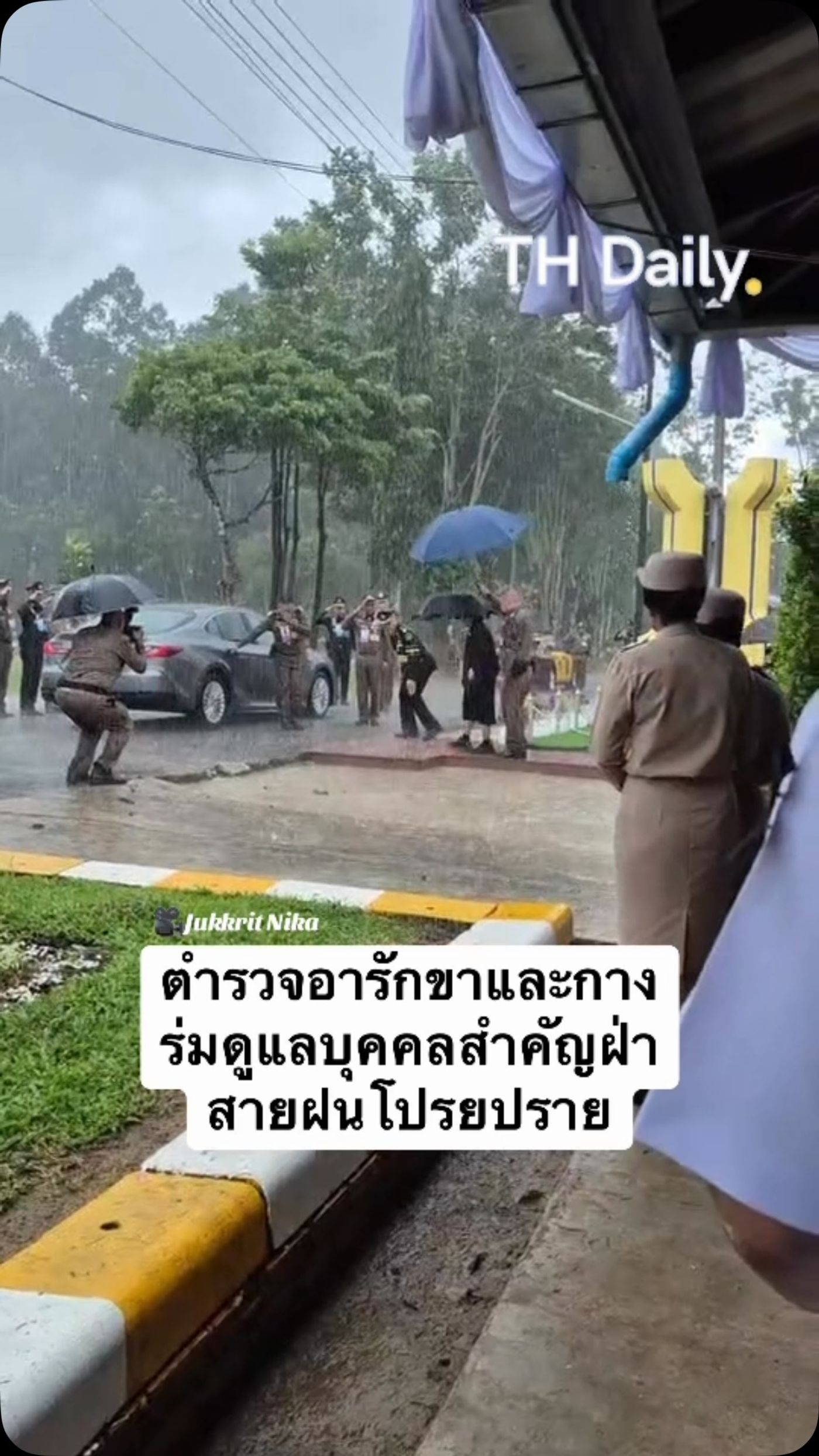 Officers hold umbrellas beside car in heavy rain