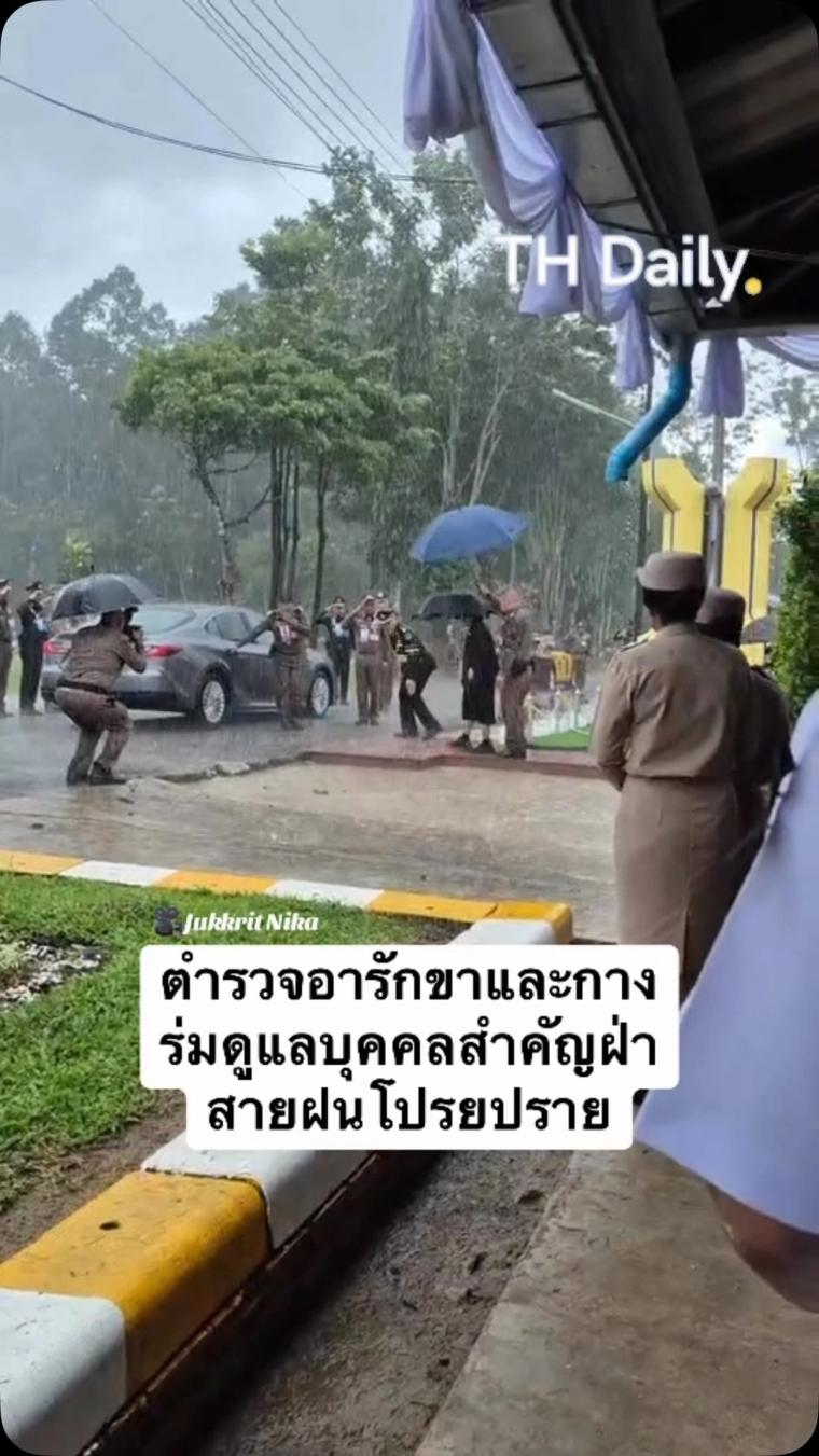 Officers hold umbrellas beside car in heavy rain