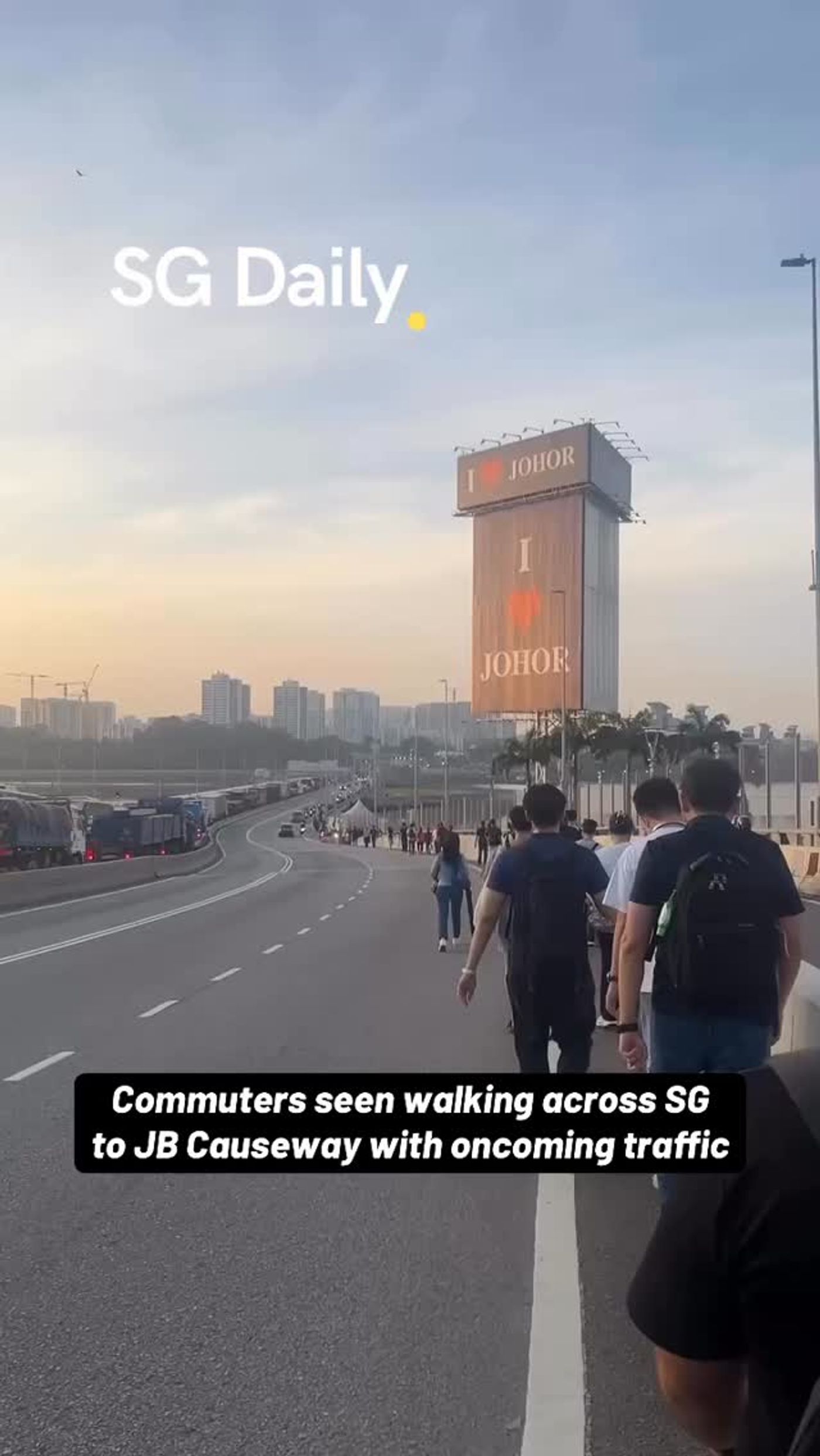 Commuters walk across Causeway towards JB beside oncoming traffic