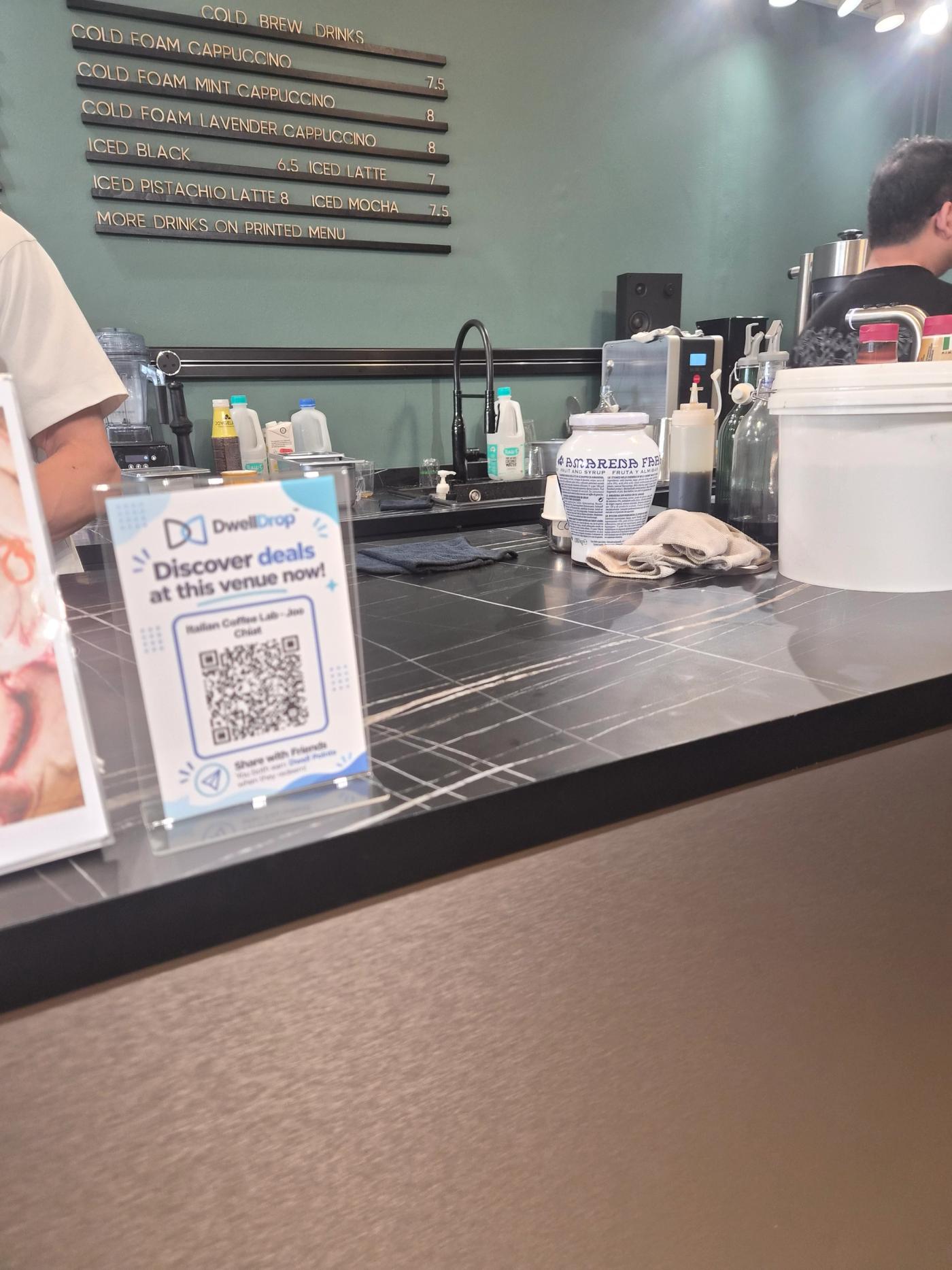 A DwellDrop QR display on the counter at Italian Coffee Lab.