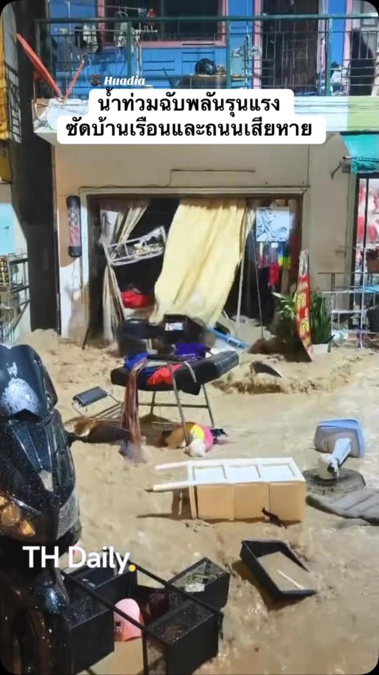 Muddy floodwater rushes past homes and scattered belongings