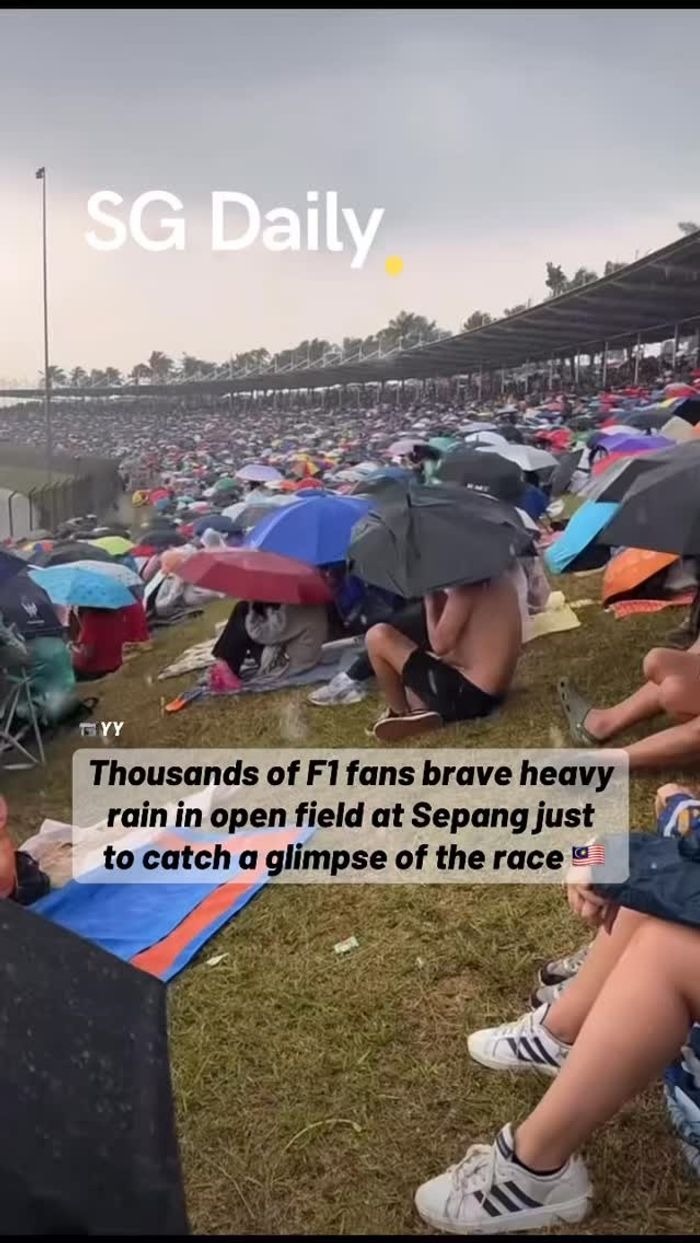 Thousands of F1 fans brave heavy rain in open field at Sepang just to catch a glimpse of the race
