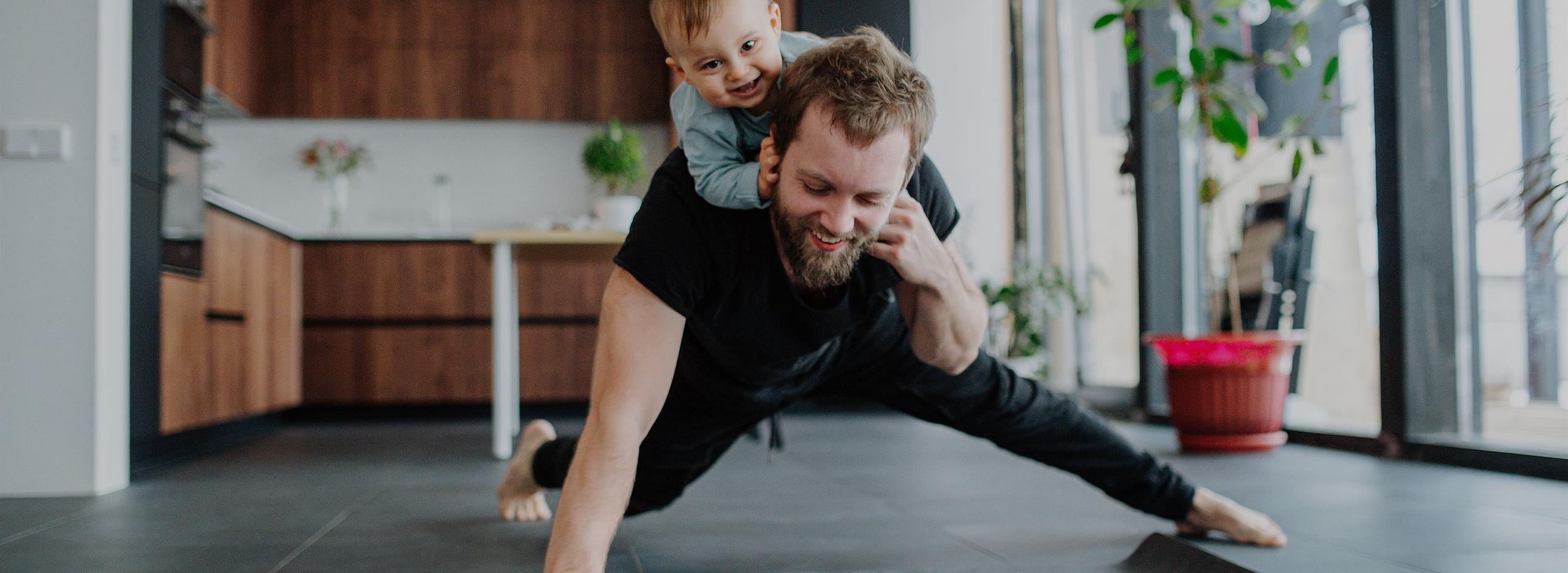 A man doing floor exercises with a baby on his back