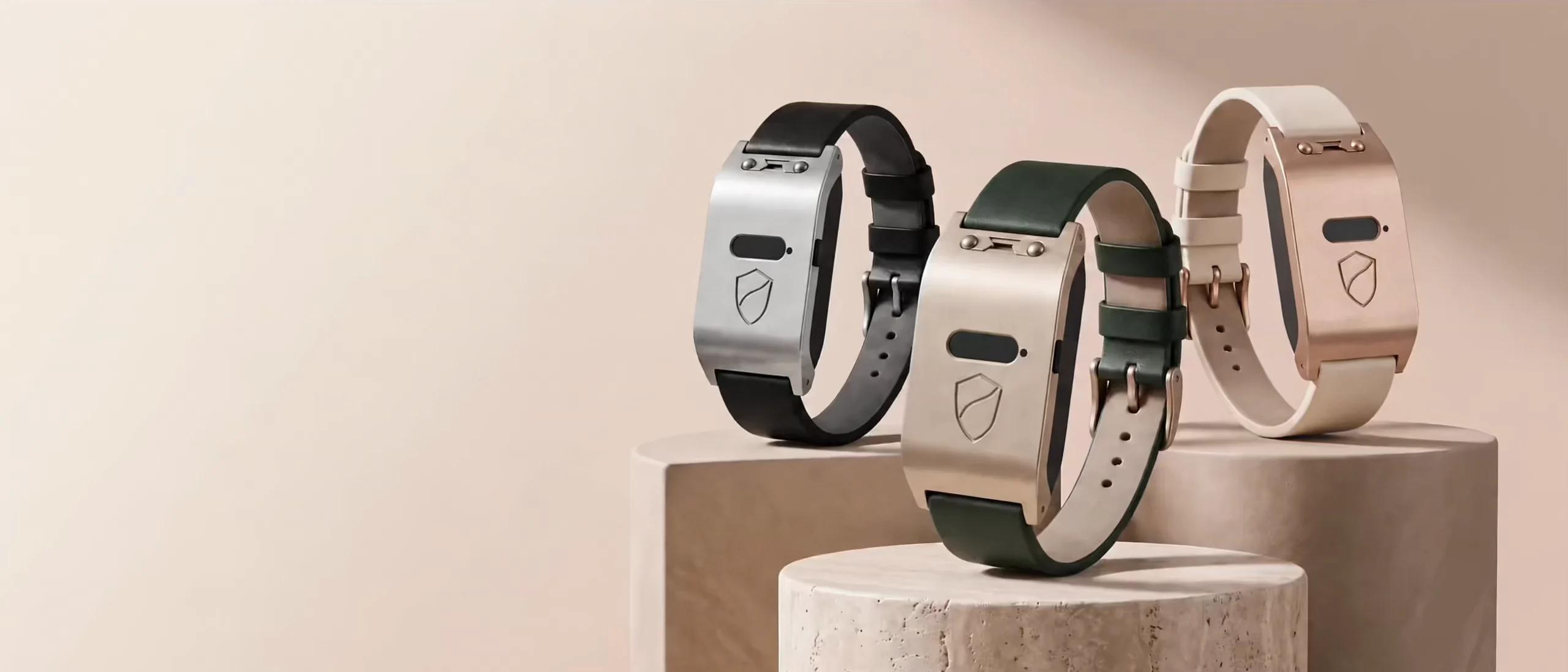 Three Brava Arc bracelets on stone plinths: black and silver, champagne and forest green, rose gold and ivory