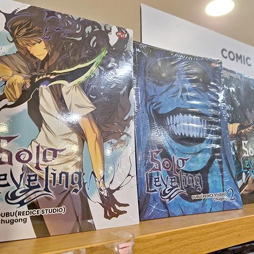 Una vista de cerca de volúmenes de manga "Solo Leveling" envueltos en plástico en un estante de una tienda.