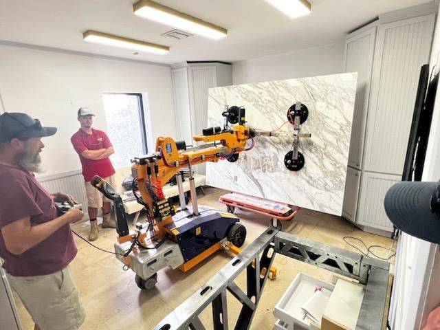 Quattrolifts vacuum lifter setting a white marble slab vertically as two operators control the machine