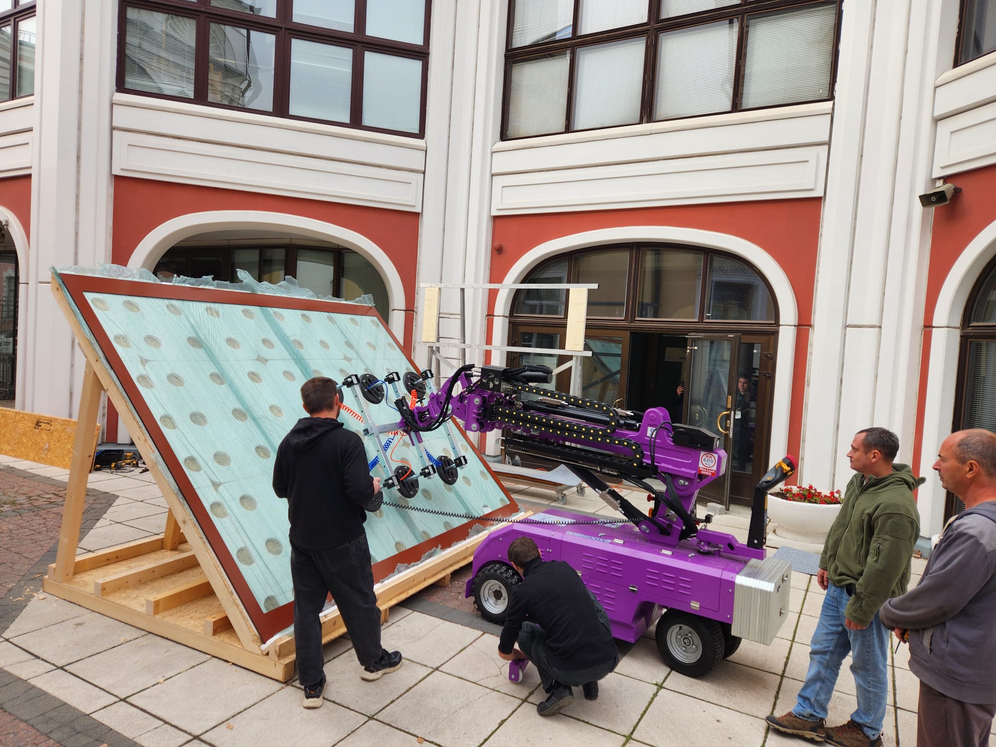 Quattrolifts vacuum lifter handling a large glass panel in an ornate building courtyard during a glass install