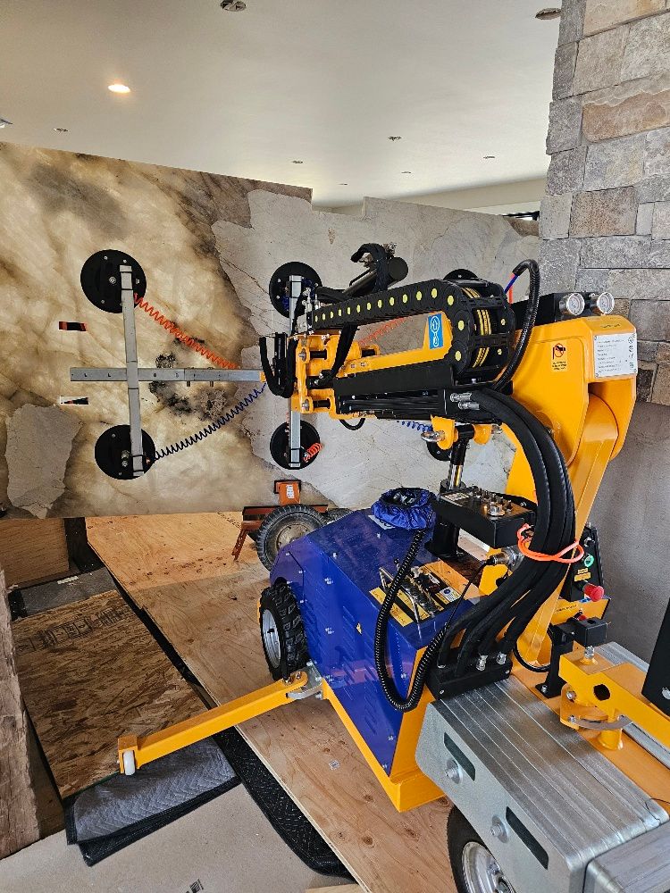 Quattrolifts vacuum lifter handling a dark veined granite slab against a stone surround on site