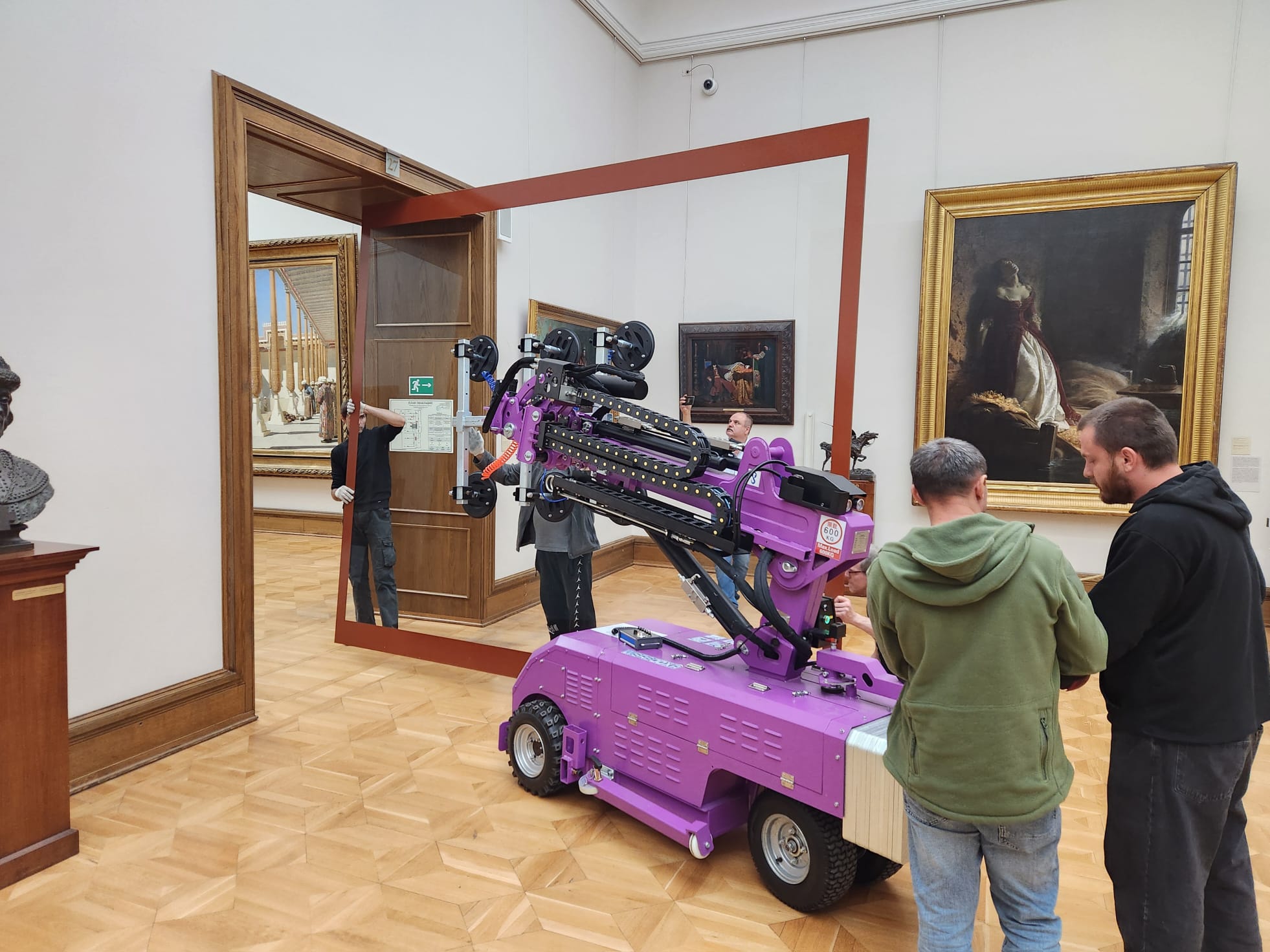 Quattrolifts powered vacuum lifter positioning glass through a doorway in an art gallery as installers look on