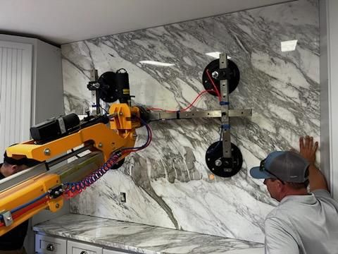 Close-up of Quattrolifts suction pads gripping a white marble slab as an operator steadies it