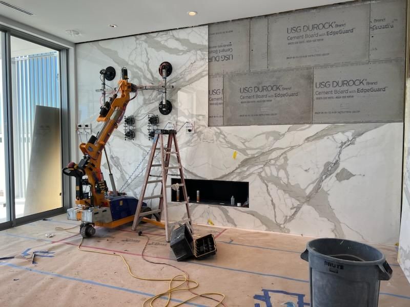 Quattrolifts lifter positioning a large white Calacatta marble slab on a fireplace wall during install