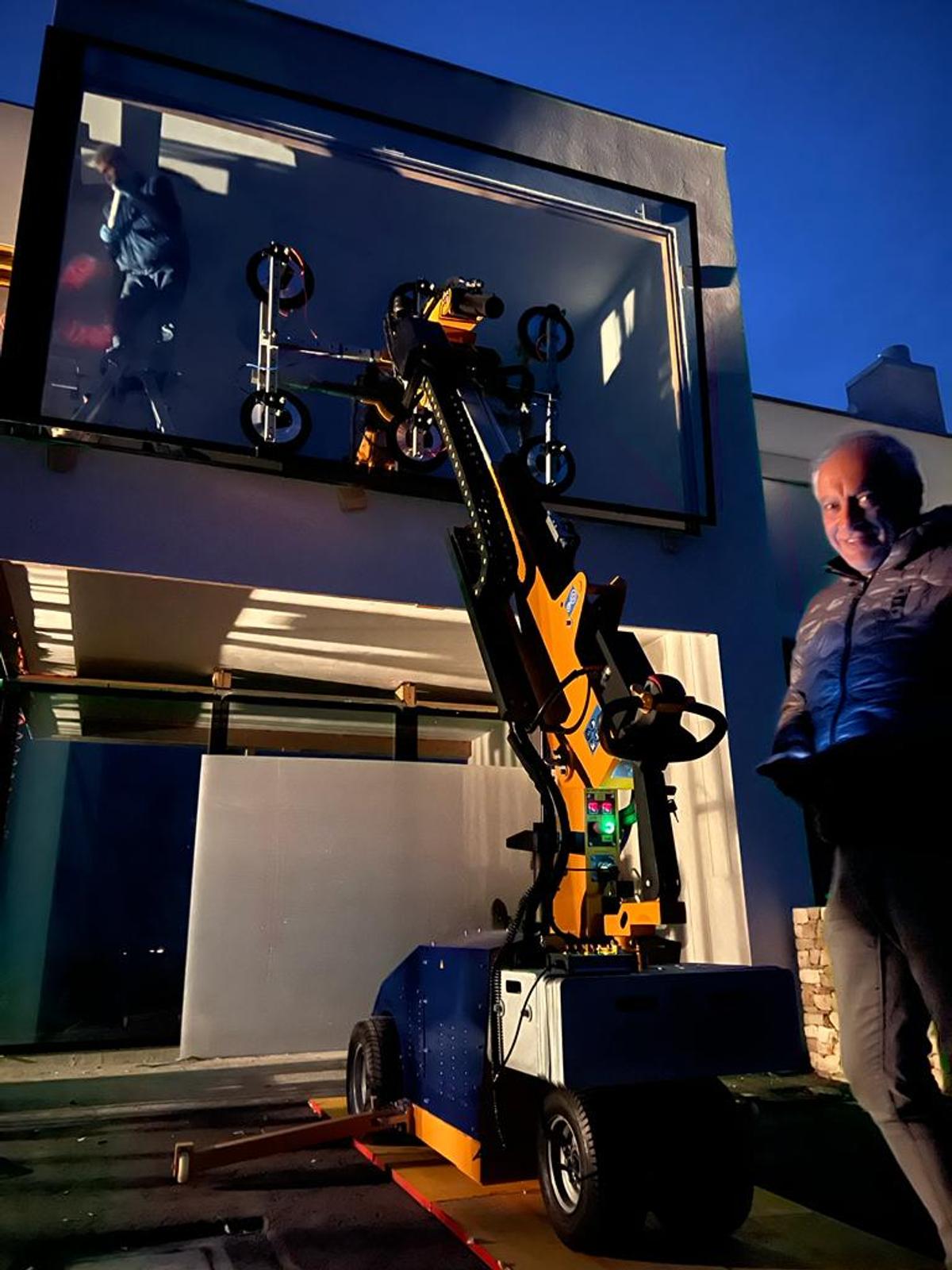 Quattrolifts Vector robotic vacuum lifter installing a large glass panel at a coastal villa