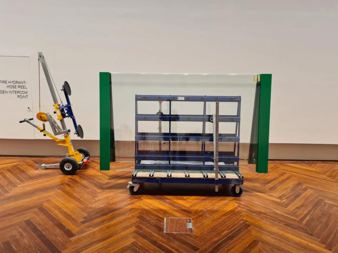 Quattrolifts vacuum glass lifter beside a large framed glass case in a museum gallery with timber floor