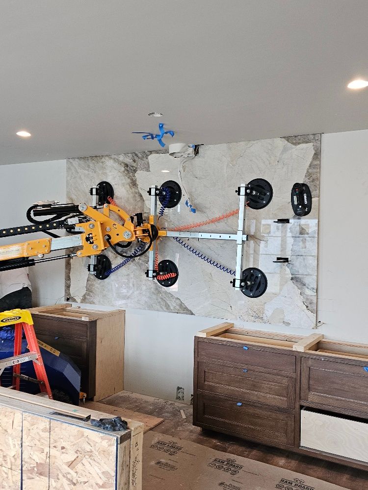 Quattrolifts suction frame mounting a grey and white marble wall panel above new cabinetry