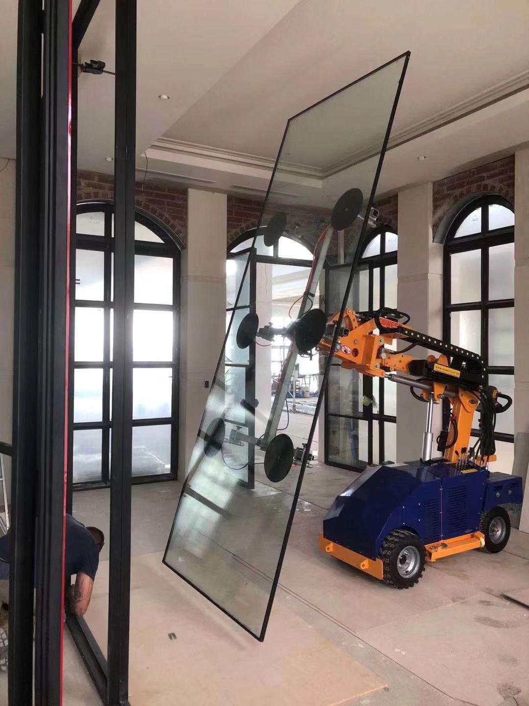 Quattrolifts robotic glass lifter carrying a large glass partition pane in a heritage museum interior with arched windows