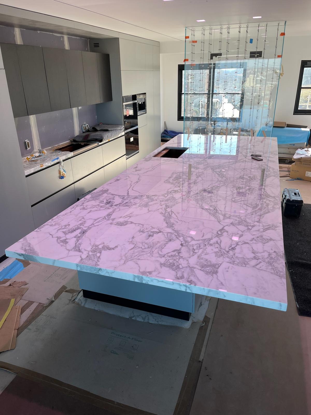 Quattrolifts Omni lifter holding a glass panel above a finished marble kitchen island