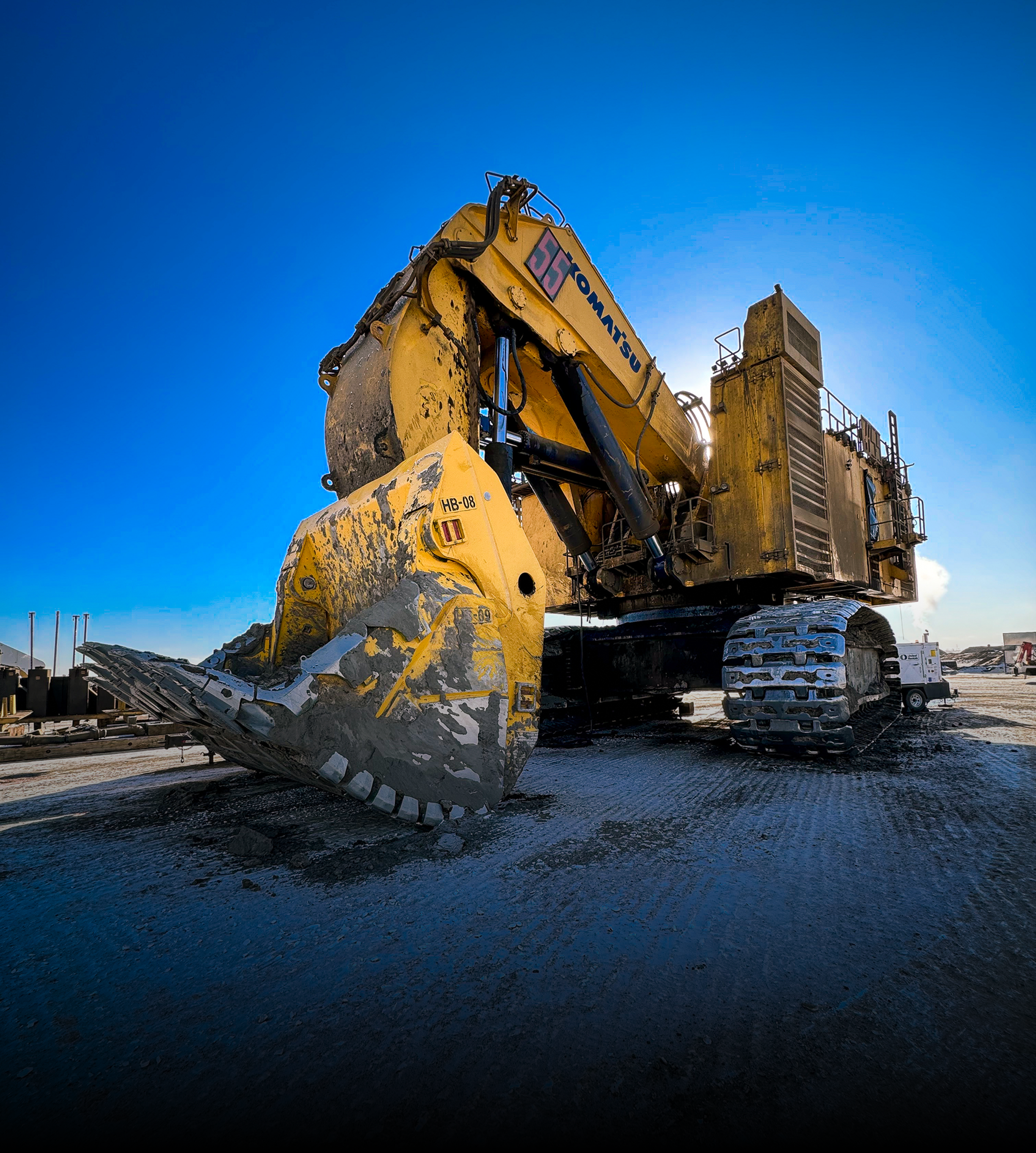 Yellow Komatsu 55 hydraulic excavator parked in a snowy mine.