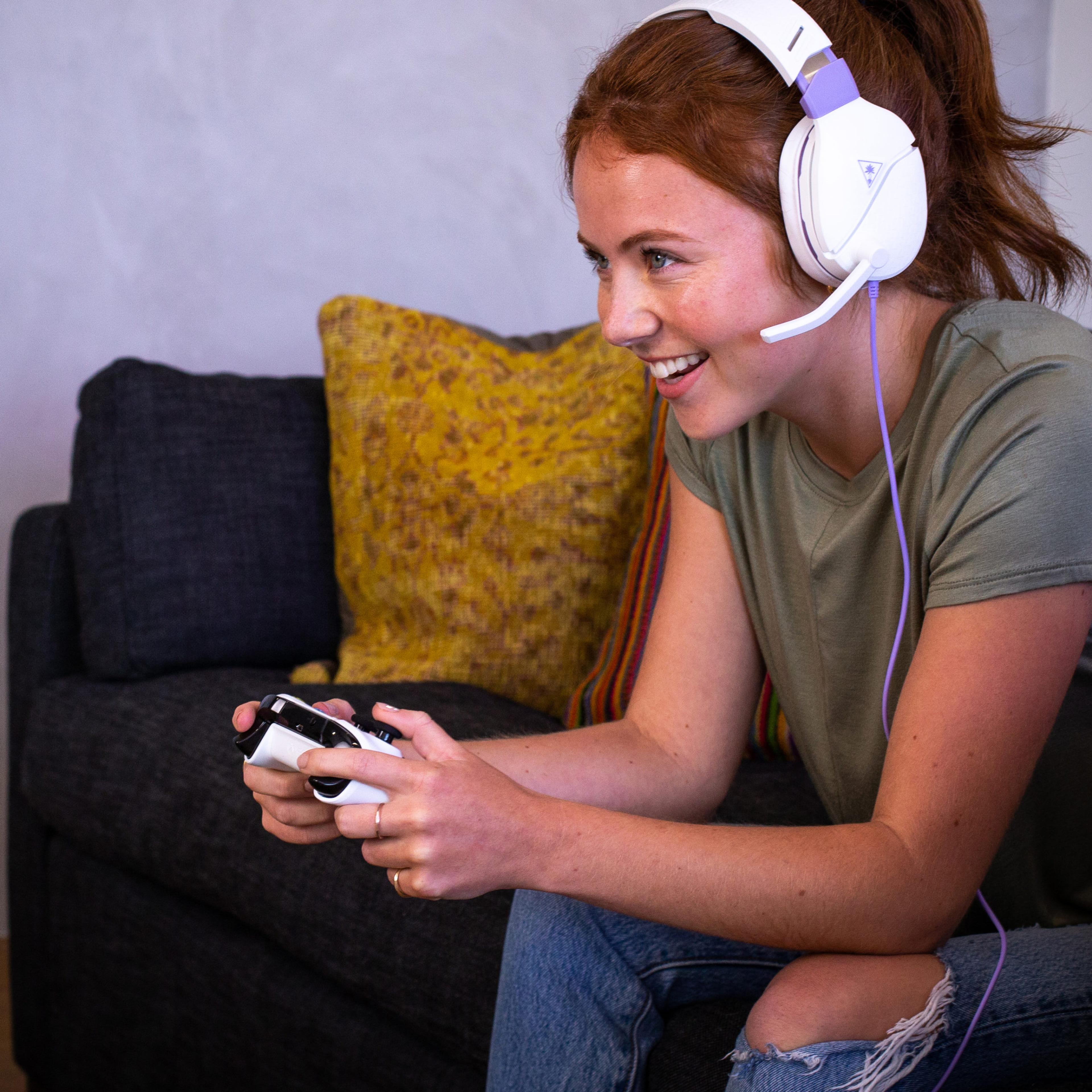 a woman wearing headphones is playing a video game on a couch .