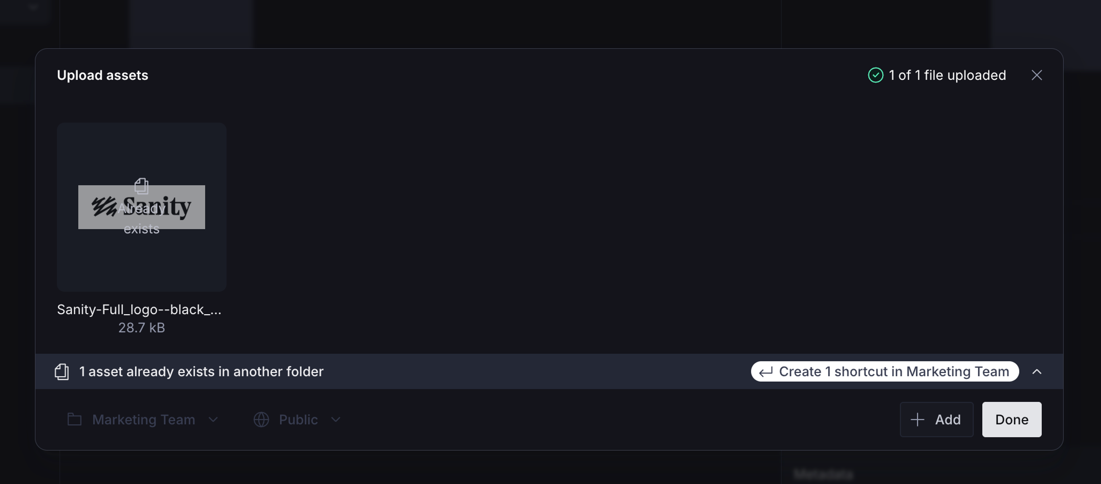 An "Upload assets" modal in a dark interface, showing a Sanity logo upload with "1 of 1 file uploaded" and an option to create a shortcut in "Marketing Team" for an existing asset.