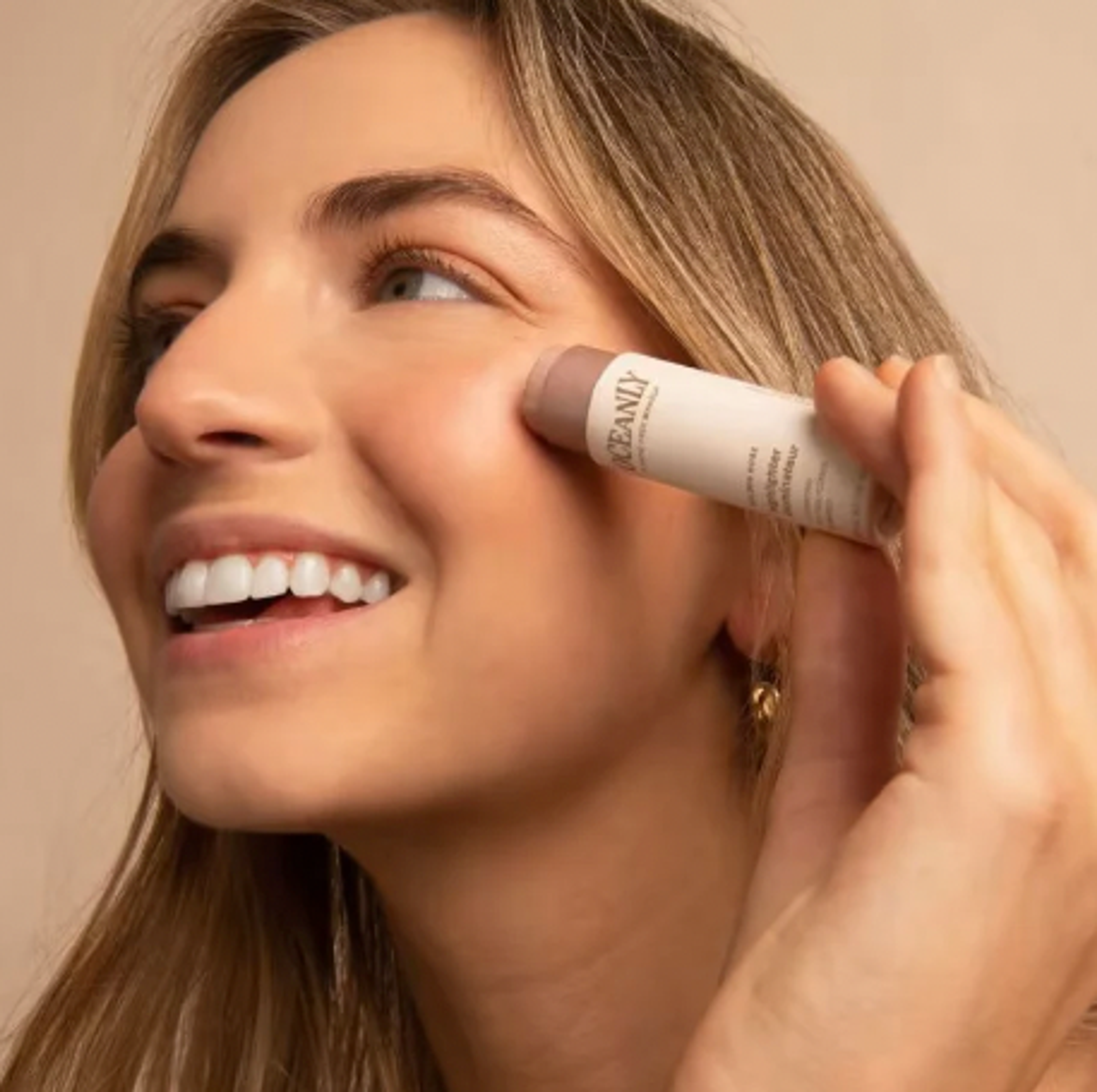 a woman is smiling while applying oceanic makeup to her face