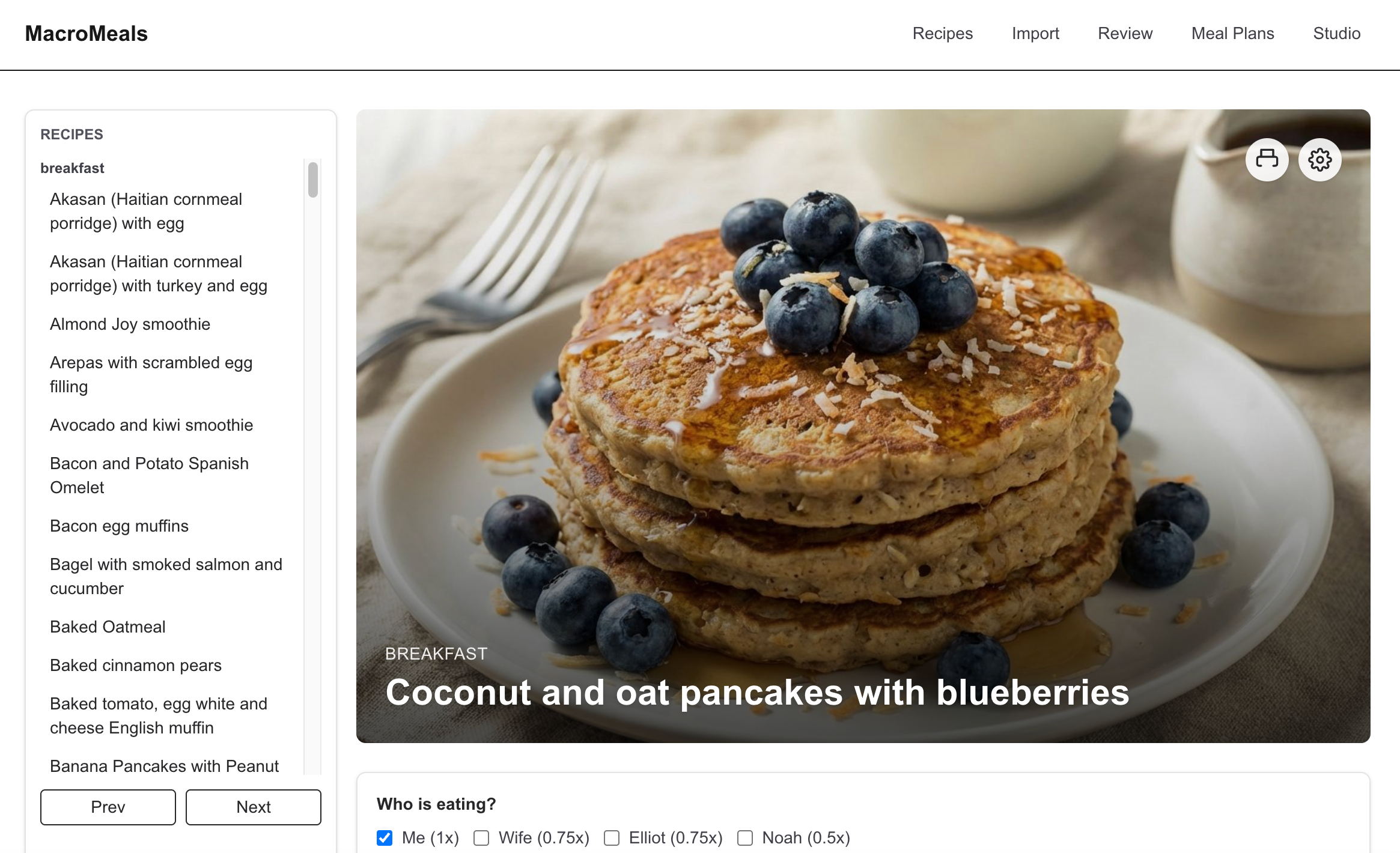 Stack of coconut and oat pancakes topped with blueberries and syrup, displayed on a plate.