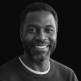Smiling Black man in a black and white headshot.