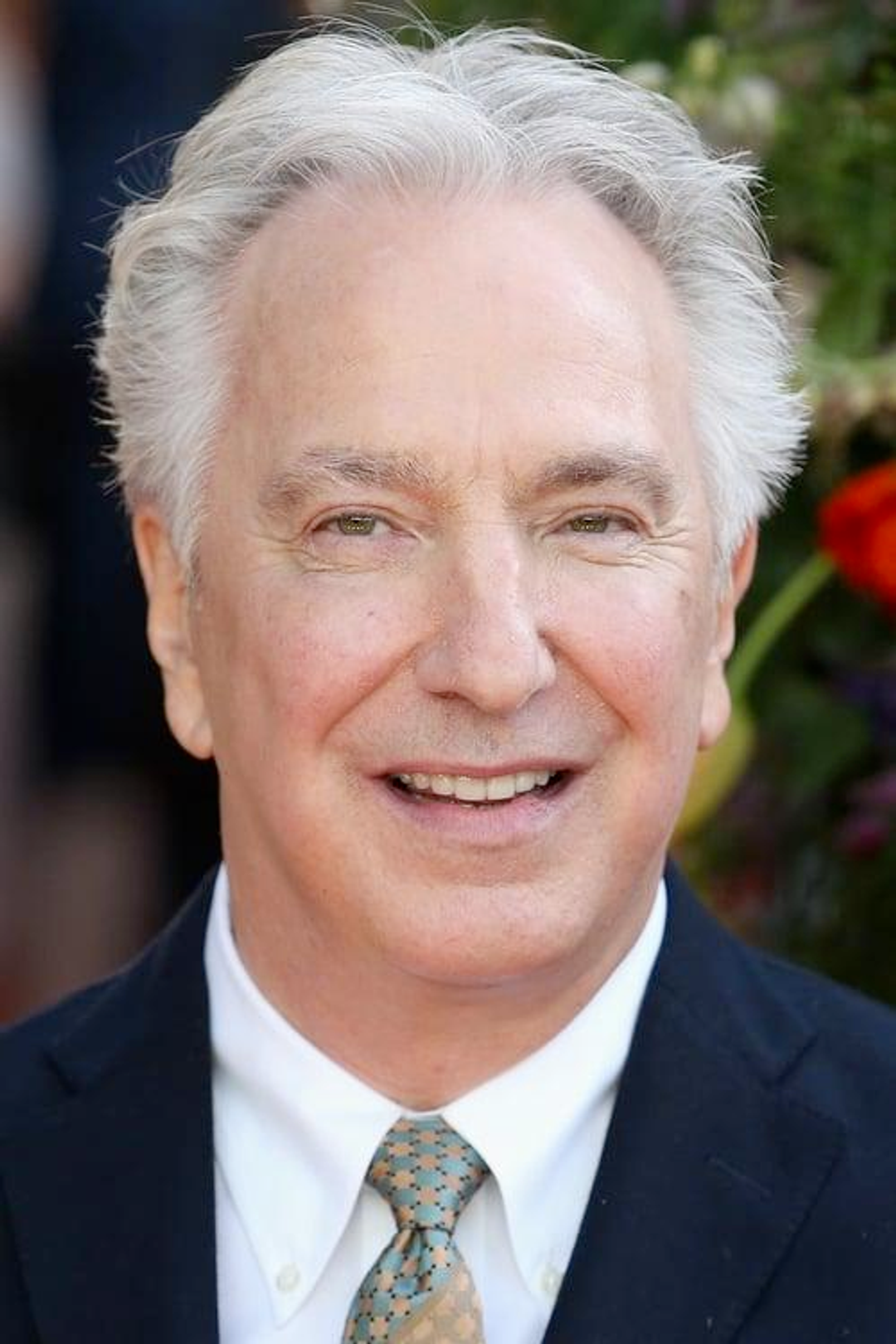 The late, great actor Alan Rickman smiling awkwardly at the camera