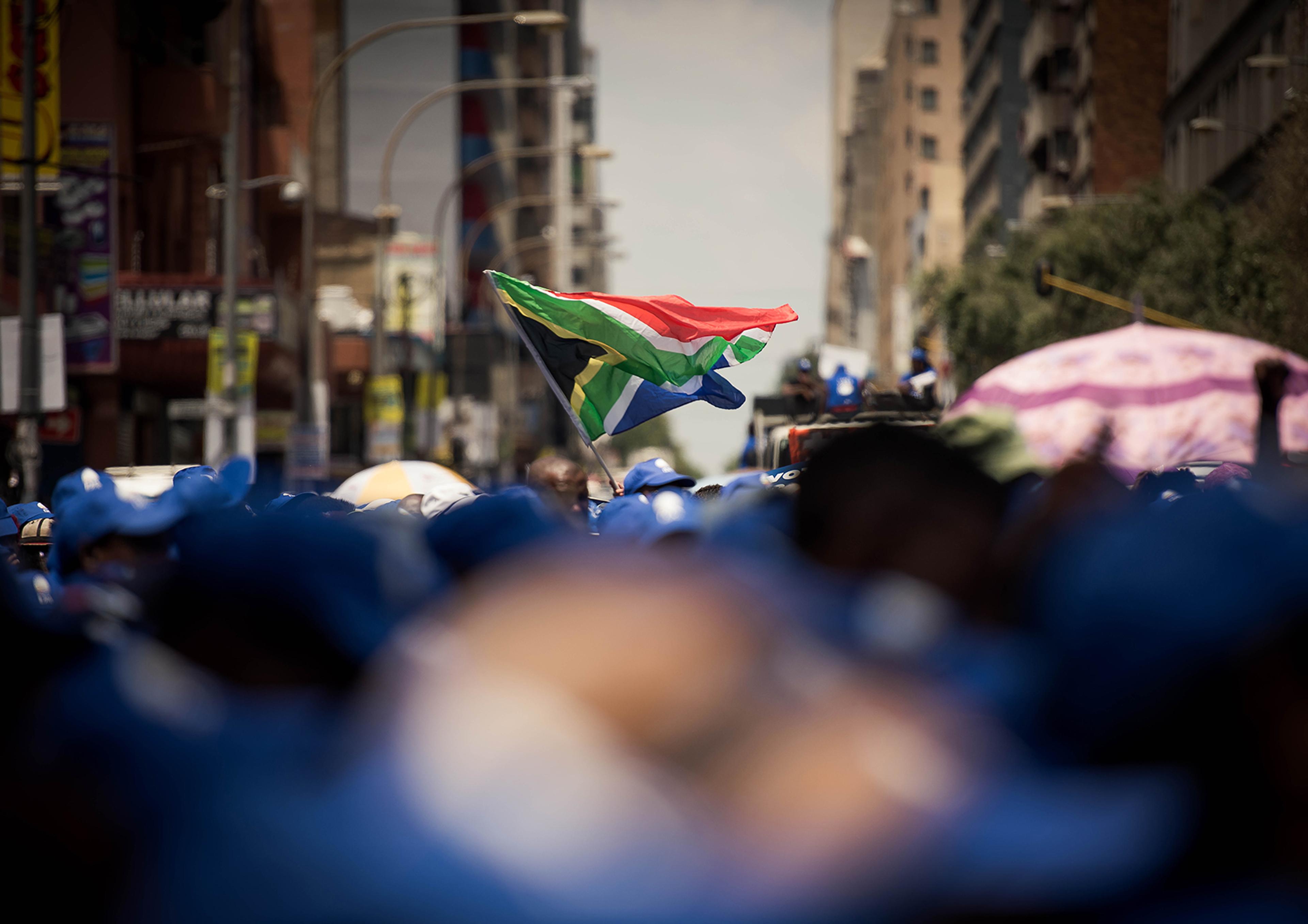 a person is holding a south african flag in a crowd of people .