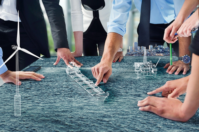 People around a meeting table pointing at projections of container ship, windmills, and oil rig.