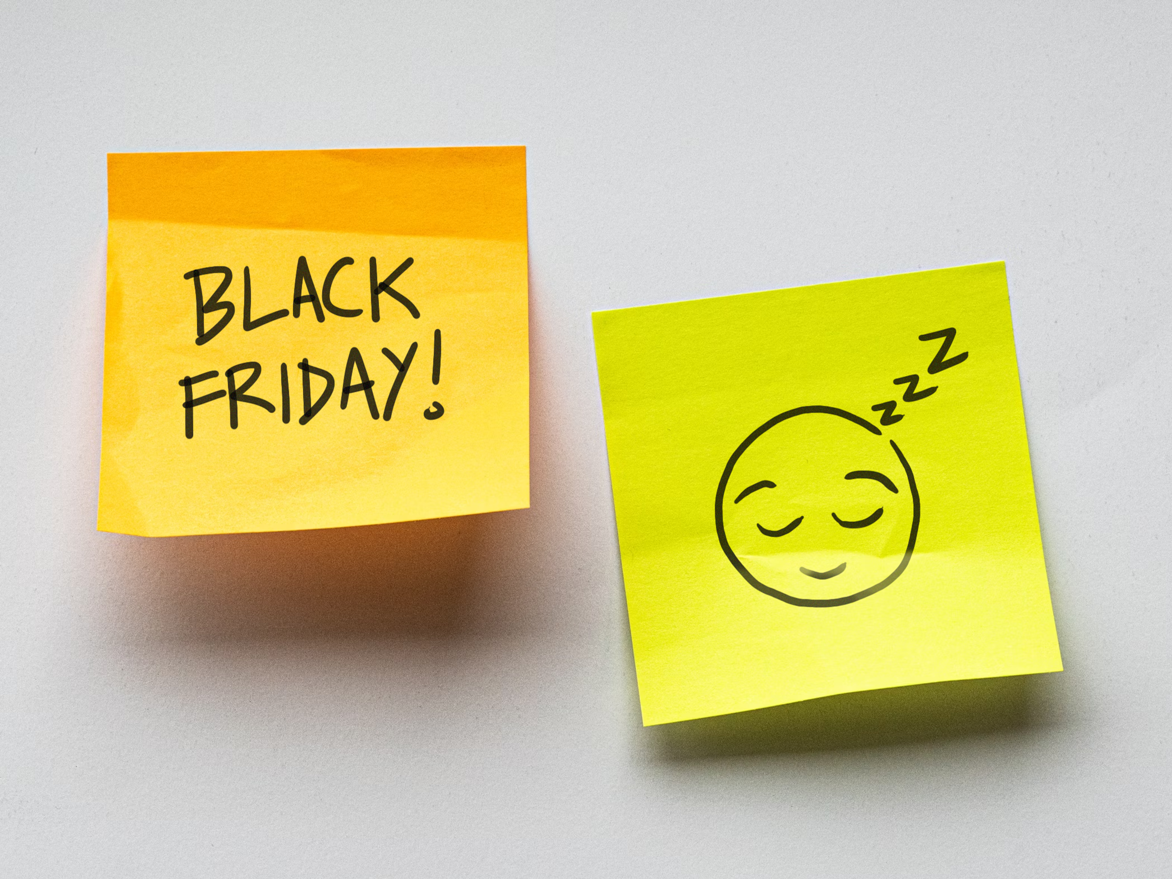 A post it note with the text "Black Friday!", next to it another note with a contented sleeping emoji drawn on it.