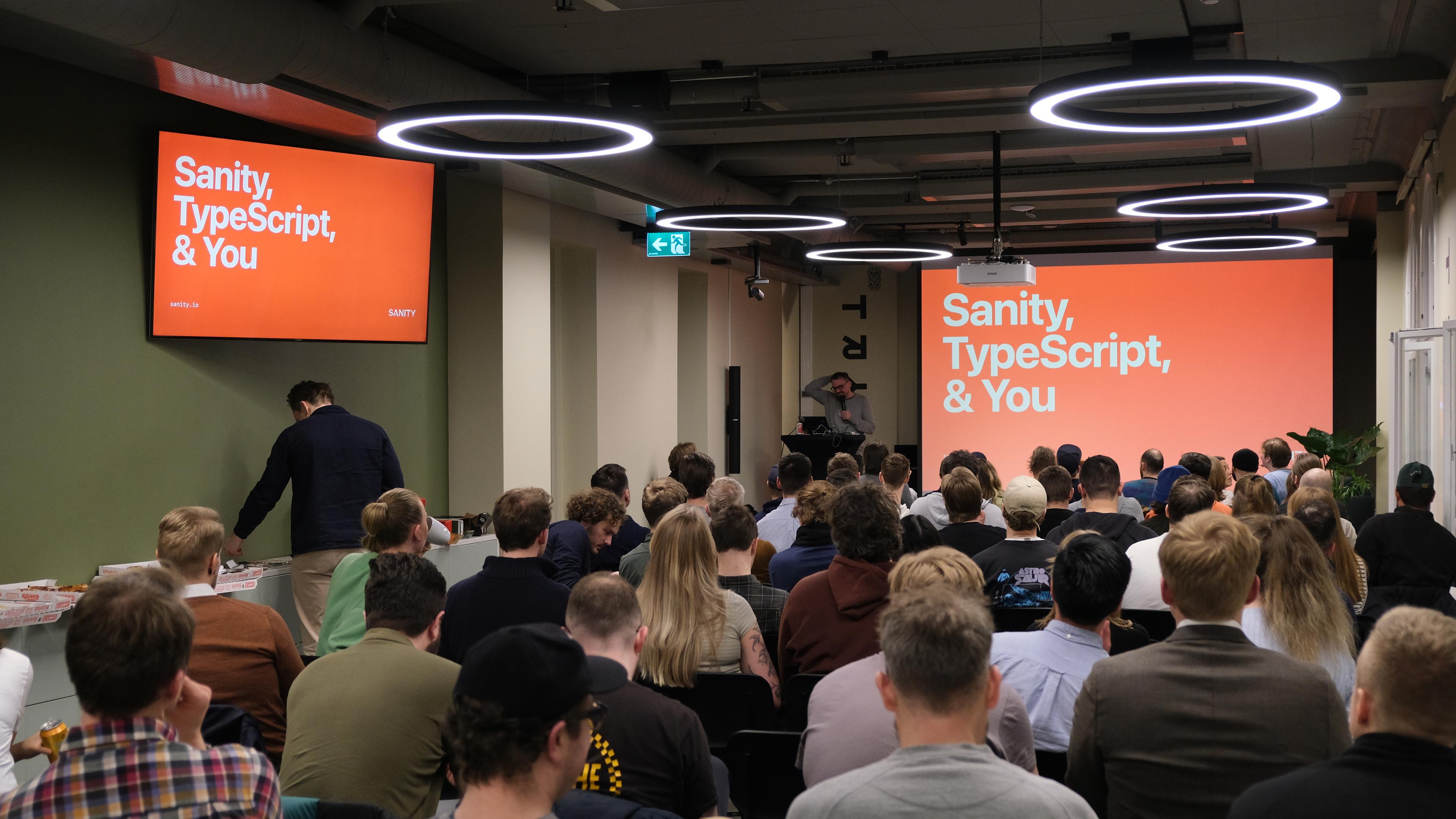 A group of people watching a presentation called "Sanity, TypeScript, & You"